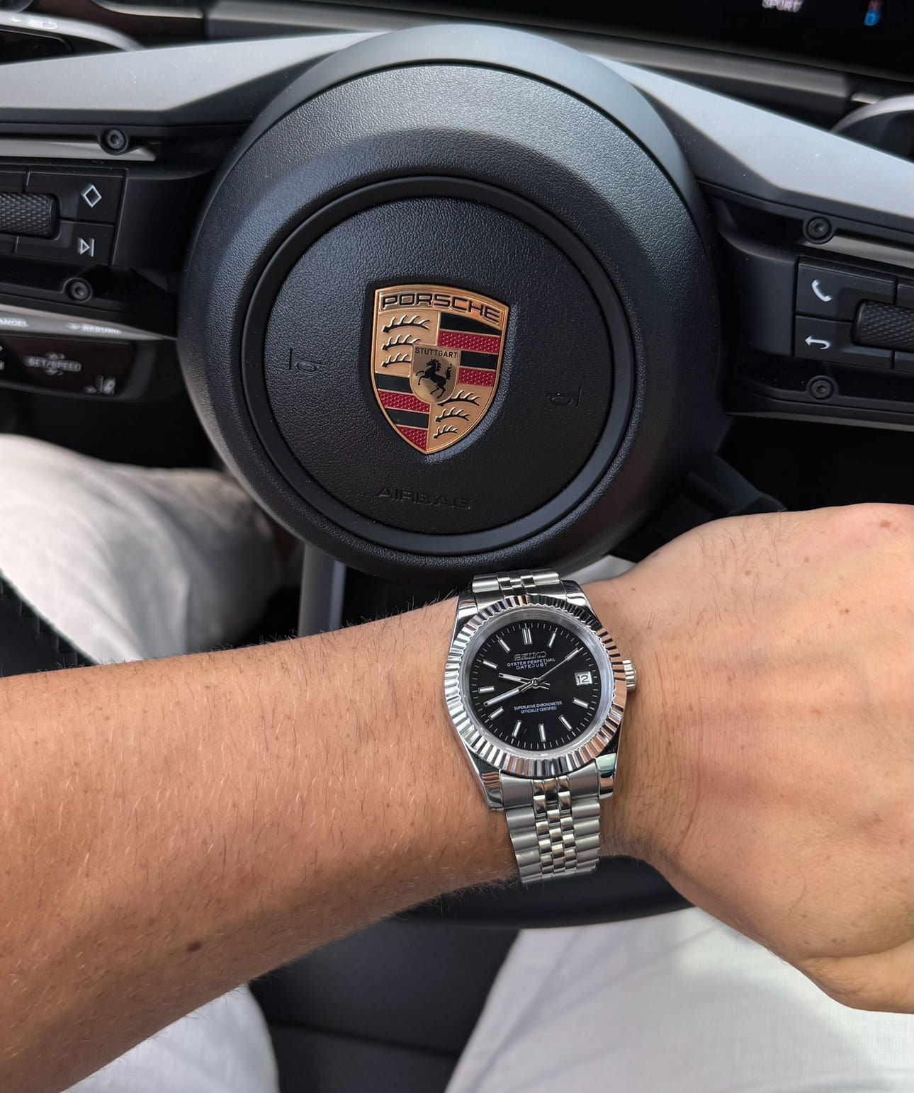 Die SeikoMod Datejust Schwarz mit Strichindizes getragen am linken Handgelenk, im Hintergrund der Innenraum eines Porsches.